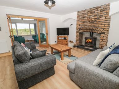 A living room with two grey sofas a wooden coffee table a wood burning stove set in a brick fireplace and a television at 24 Hauxley Links Low Hauxley near Amble