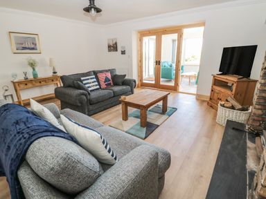 A living room with two sofas coffee table wooden cabinet and television at 24 Hauxley Links in Low Hauxley near Amble