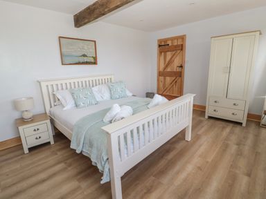A bedroom with a white wooden bed two pillows with birds a nightstand lamp a wooden door and a white wardrobe at 24 Hauxley Links Low Hauxley near Amble