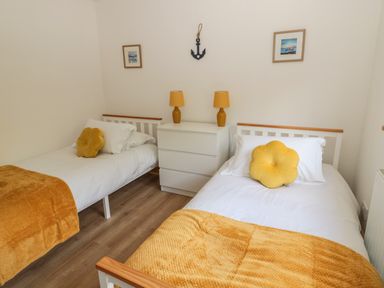 A bedroom with two single beds a white drawer unit and yellow pillows at 24 Hauxley Links in Low Hauxley near Amble