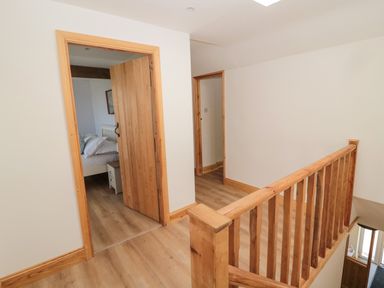 A hallway with wooden floor and staircase leading to rooms with wooden doors at 24 Hauxley Links in Low Hauxley near Amble