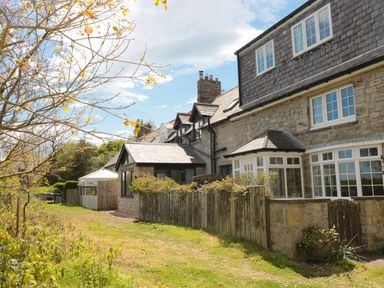 Stone and brick houses with fenced yards and a tree with yellow leaves at 24 Hauxley Links in Low Hauxley near Amble