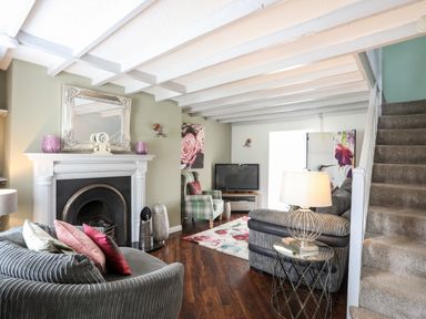 A living room with a fireplace sofas a television and stairs at Bryn Peris in Moelfre