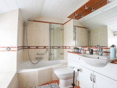 A bathroom with a bathtub shower combo a toilet and a sink with a countertop at Bryn Peris in Moelfre