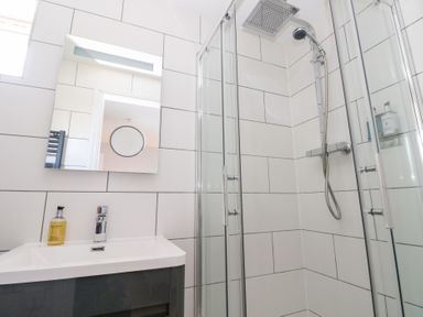 A bathroom with a sink a mirror and a glass enclosed shower at Cambrie in Tenby