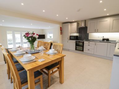 A kitchen and dining area with wooden dining table set for six and gray cabinets at Hen Dy Bryn Mawndy in Melin y Wig near Corwen