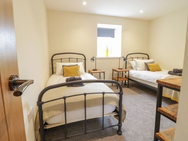 A bedroom with two single metal frame beds bedside tables and a window at Hen Dy Bryn Mawndy Melin y Wig near Corwen