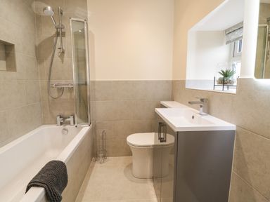 A bathroom with a bathtub shower toilet sink and a window with a plant on the sill at Hen Dy Bryn Mawndy Melin y Wig near Corwen