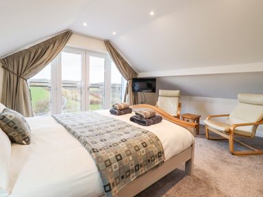 A bedroom with a bed and two chairs by a window with curtains at Hen Dy Bryn Mawndy in Melin y Wig near Corwen