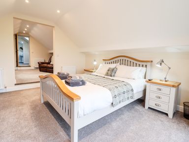 A bedroom with a bed side tables and a brown armchair at Hen Dy Bryn Mawndy in Melin y Wig near Corwen
