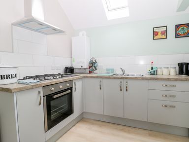 A kitchen with oven stovetop sink kettle bread container and wall art at Robins Nest Cottage in Brandesburton