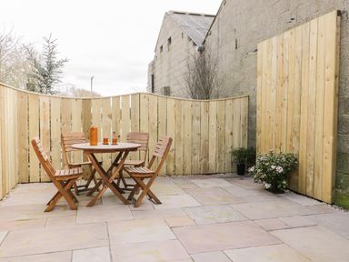 An outdoor patio area with wooden table and four chairs next to a wooden fence at Robins Nest Cottage Brandesburton
