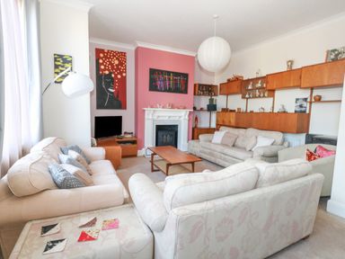 A living room with sofas a coffee table a fireplace and paintings at Victorian Town House in Weymouth