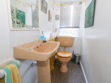 A bathroom with a beige sink and toilet with a wooden seat cover at Victorian Town House in Weymouth