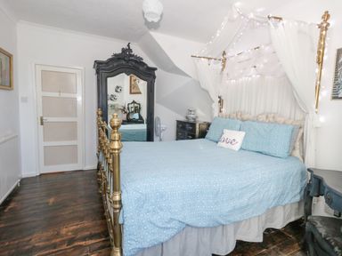 A bedroom with a brass bed with blue bedding and a black ornate mirror at Victorian Town House in Weymouth