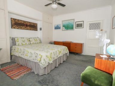A bedroom with a bed butterfly bedspread wooden dresser green chair and decorative wall art at Victorian Town House in Weymouth