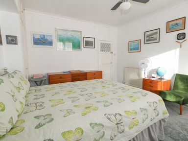 A bedroom with a bed covered in butterfly print bedding a green chair wooden dressers a globe and framed pictures on the walls at Victorian Town House in Weymouth