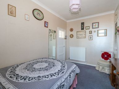 A bedroom with a bed a chair with a cushion multiple framed pictures a radiator and a mirror at Victorian Town House in Weymouth