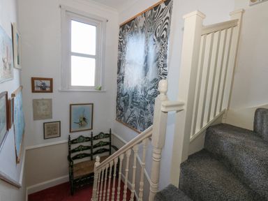A staircase with gray carpet a white wooden banister and framed pictures on the walls at Victorian Town House in Weymouth