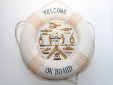 A decorative life preserver with knots and a small boat model hanging on a wall at Victorian Town House in Weymouth