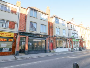 A street view of brick buildings with shops including a barbershop at Victorian Town House Weymouth