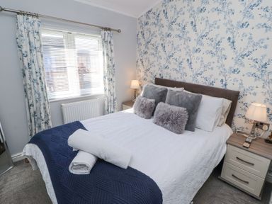 A bedroom with a bed covered with white bedding and blue throw blanket at Duckling Lodge in South Lakeland Leisure Village