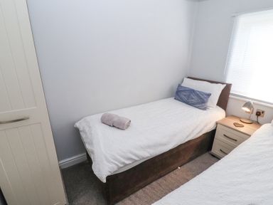 A bedroom with two single beds a nightstand with a lamp and a wardrobe at Duckling Lodge in South Lakeland Leisure Village
