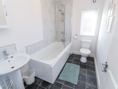 A bathroom with a bathtub shower combination a sink toilet and window at Duckling Lodge South Lakeland Leisure Village