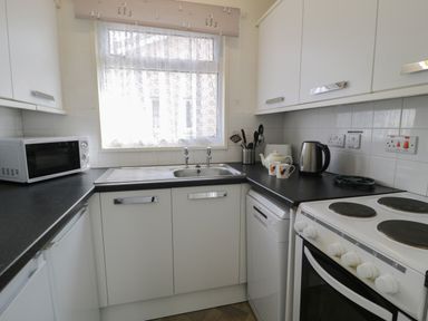 A kitchen with a microwave oven sink electric stove kettle and utensils at Hafod-y-Gors in Fairbourne