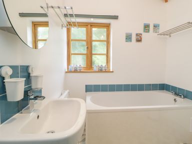 A bathroom with a sink and bathtub near a window at The Old Haybarn in Ipplepen