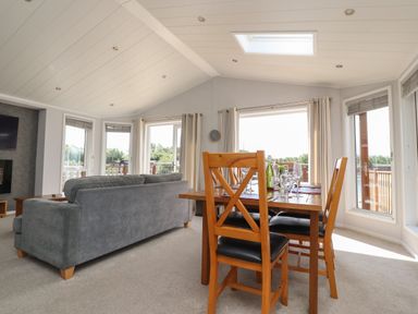 A living room with a gray sofa and wooden dining table with chairs at Mereside South lakeland Leisure Village near Carnforth