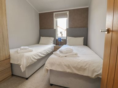 A bedroom with two single beds a window and a bedside table at Mereside South lakeland Leisure Village near Carnforth