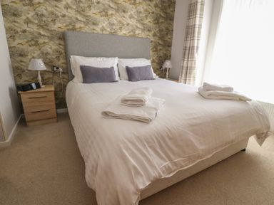 A bedroom with a double bed bedside tables lamps and folded towels at Mereside South lakeland Leisure Village near Carnforth