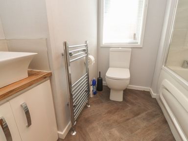 A bathroom with a toilet a towel rail a sink on a wooden countertop and a bathtub at Mereside South lakeland Leisure Village near Carnforth