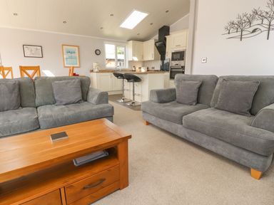 A living room with two gray sofas a wooden coffee table and a kitchen with bar stools at Mereside South lakeland Leisure Village near Carnforth