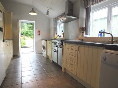 A kitchen with cabinets appliances and an open door to the outside at The Farmhouse in Newport Pembrokeshire
