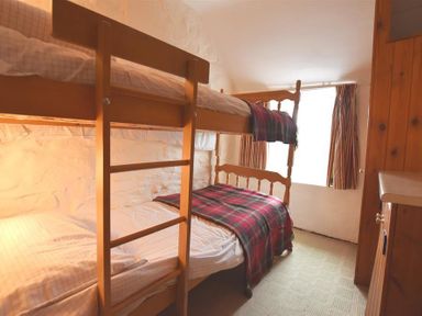 A bedroom with wooden bunk beds and a window with striped curtains at The Farmhouse in Newport Pembrokeshire