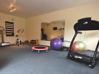 A home gym with exercise equipment including a treadmill exercise bike rowing machine large mirror and stability balls at The Farmhouse in Newport Pembrokeshire