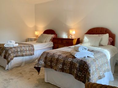 A bedroom with two single beds a wooden dresser and two lamps at The Farmhouse in Newport Pembrokeshire
