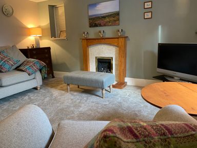 A living room with a sofa a lamp a wooden table a television and a fireplace at The Farmhouse in Newport Pembrokeshire