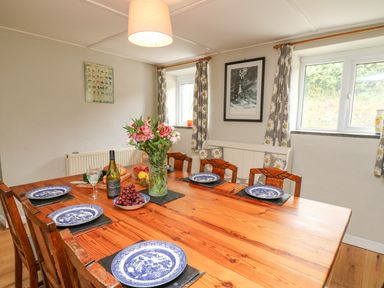 A dining room with a wooden table set with blue and white plates and flowers at The Farmhouse in Newport Pembrokeshire
