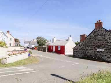 A road intersection with stone and brick houses and flower beds at Bwthyn Alarch in Trefin St Davids Pembrokeshire