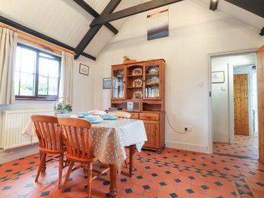 A dining area with wooden chairs and table with dishes next to a wooden cabinet with plates in a room at Bwthyn Alarch in Trefin St Davids Pembrokeshire