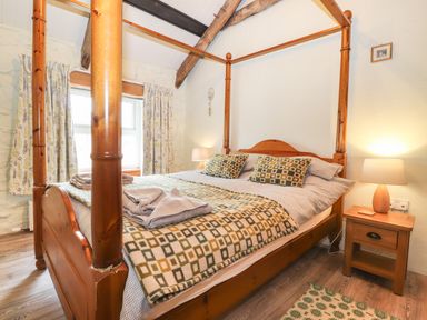 A bedroom with a four poster wooden bed bedside table and lamp at Bwthyn Alarch in Trefin St Davids Pembrokeshire