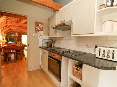 A kitchen with oven stove toaster and cabinets leading to a dining area with wooden table and chairs at The Granary in Newport Pembrokeshire