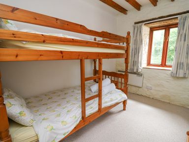 A bedroom with wooden bunk beds and a window with curtains at The Granary in Newport Pembrokeshire
