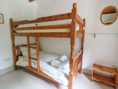 A bedroom with wooden bunk beds and towels on the lower bed at The Granary in Newport Pembrokeshire