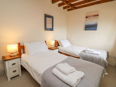A bedroom with two single beds bedside tables and lamps at The Granary in Newport Pembrokeshire