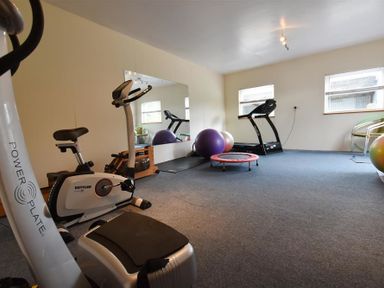 A gym room with exercise bike treadmill exercise balls a small trampoline and mirror at Stable Cottage Newport Pembrokeshire