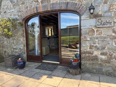 Stone exterior with an arched wooden door and potted plants outside Stable Cottage in Newport Pembrokeshire